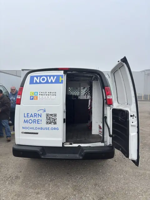 Back of van with one door open showing furniture.
